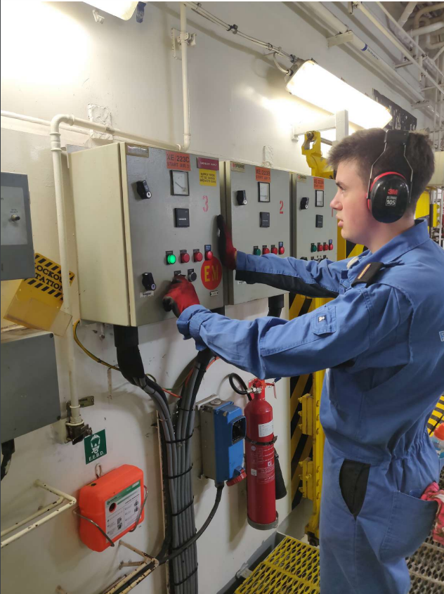 Tom working on board in the engine room in a boiler suit and PPE | National Careers Week